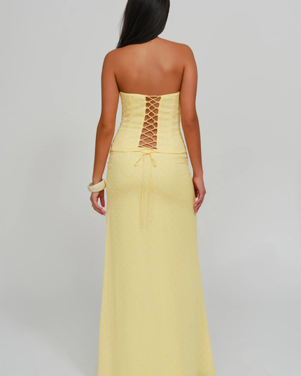Back view of yellow polka dot strapless corset maxi dress with lace-up corset detail