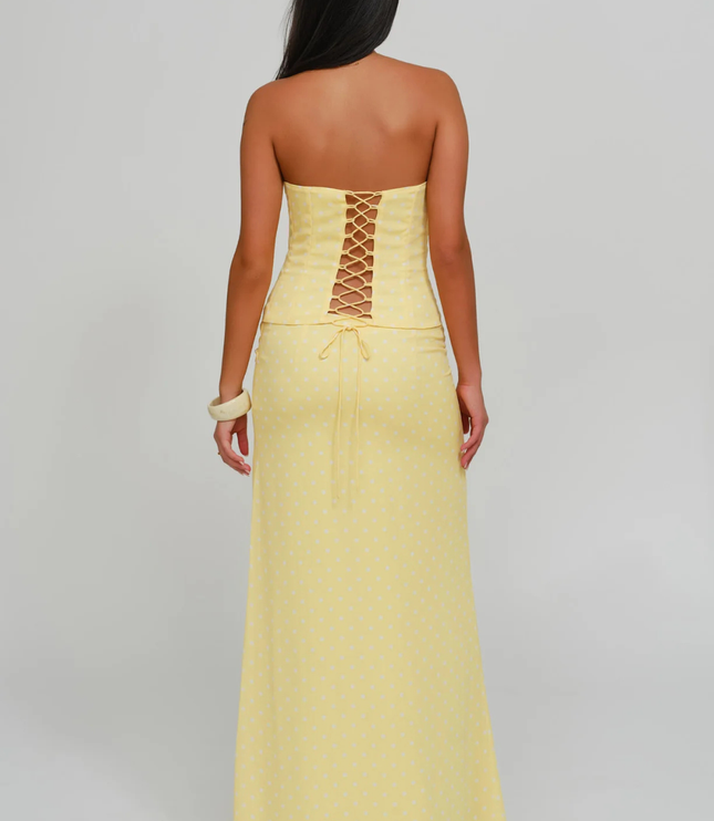 Back view of yellow polka dot strapless corset maxi dress with lace-up corset detail
