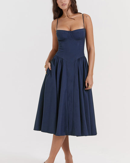 Navy corset midi dress front view with one hand in pocket, showing fitted bodice and gathered skirt