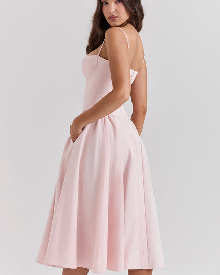 Side view of blush pink corset midi dress showing fitted waist, thin straps, and flared skirt