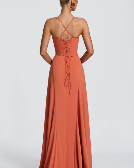Back view of coral pleated maxi dress with crisscross straps and lace-up corset tie