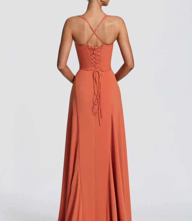 Back view of coral pleated maxi dress with crisscross straps and lace-up corset tie