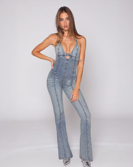 Front view of a fitted light blue denim jumpsuit with halter straps, cutout bust, and flared legs