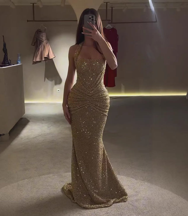 Gold sequin halter maxi dress shown in mirror with fitted shape and floor-length hem, side view