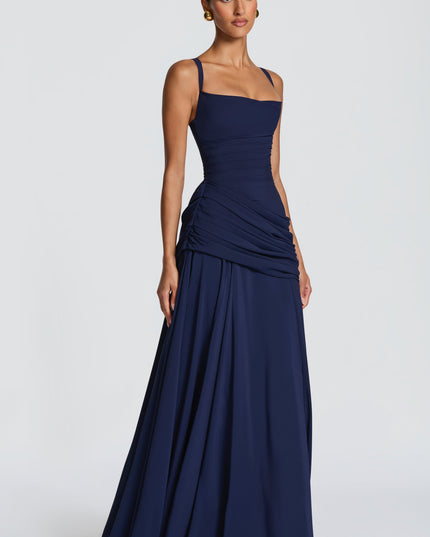 Navy satin maxi dress with square neck, ruched side drape, and full skirt, angled front view
