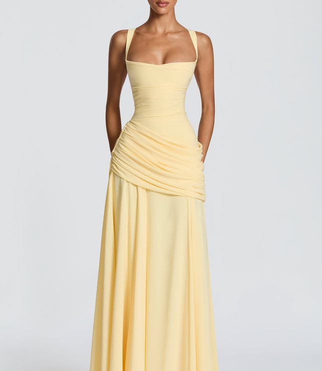 Pale yellow satin maxi dress with square neckline and side draped overlay, three-quarter front view