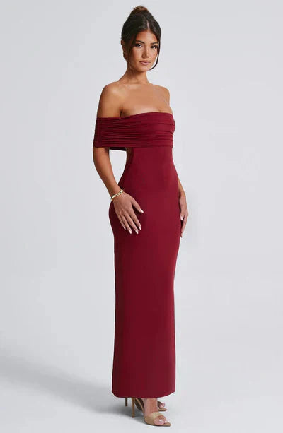 Side profile of a burgundy off-shoulder maxi dress, highlighting the fitted design and elegant floor-length skirt.