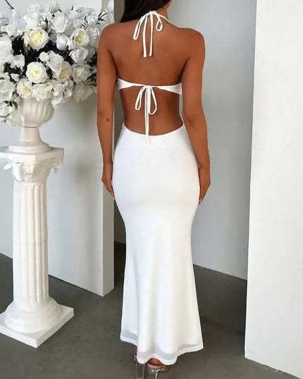 Back view of a white halter ruffle cut out backless maxi dress, showing tie details and a flowing skirt.
