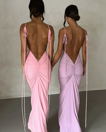 Two women from behind, showcasing a pink and a light purple pleated plunge neck backless maxi dress with tie straps.