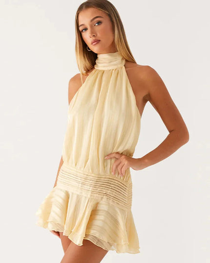 Angled view of a women's light yellow halter neck sleeveless mini dress with a layered ruffled skirt and ruched bodice.