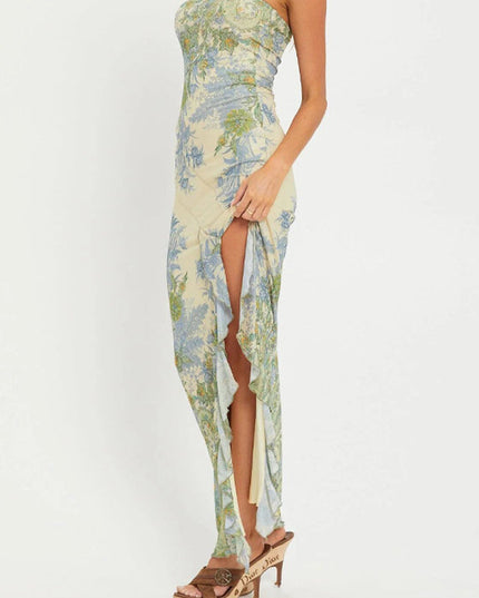 Side profile of a women's bandeau maxi dress, showcasing the intricate blue and green paisley print and ruffled high slit detail.