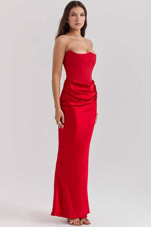 Three-quarter view of a red off-shoulder bustier draped maxi dress, for an evening or wedding event.