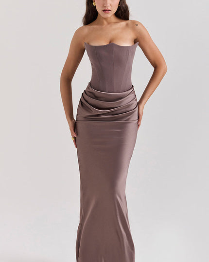 Full body shot of a women's taupe off-shoulder bustier maxi dress, featuring a fitted bodice and draped skirt.