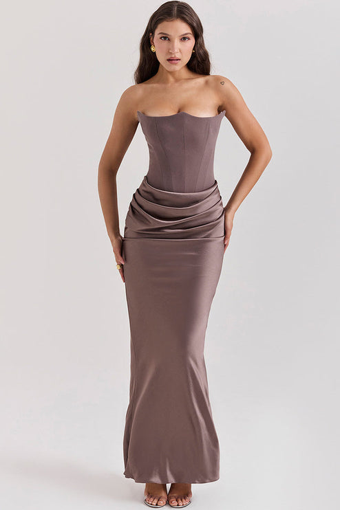 Full body shot of a women's taupe off-shoulder bustier maxi dress, featuring a fitted bodice and draped skirt.