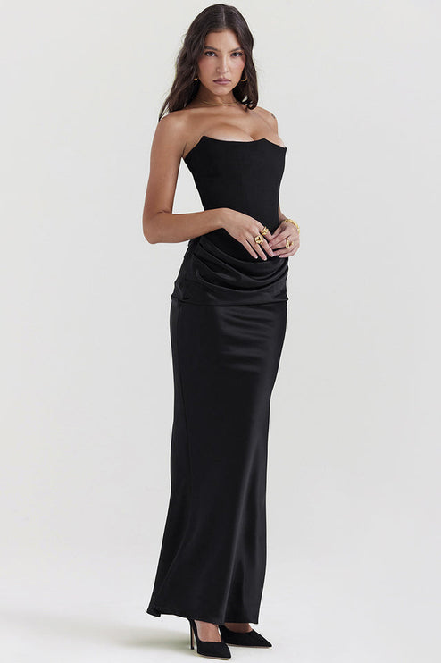 Side profile of a woman in a black off-shoulder bustier maxi dress, highlighting the fitted silhouette.