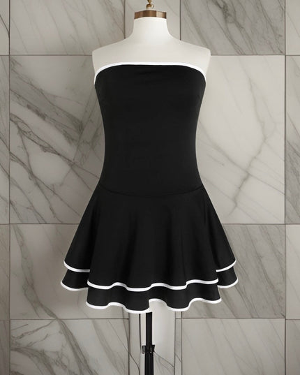 Mannequin wearing a black strapless mini dress with a fitted bodice and a tiered, ruffled skirt with white trim.