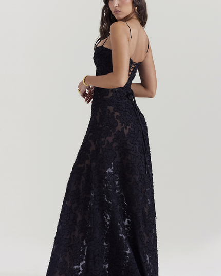 Side view of a black floral maxi dress with a lace-up corset back and thin spaghetti straps, showcasing the intricate floral pattern and full skirt.