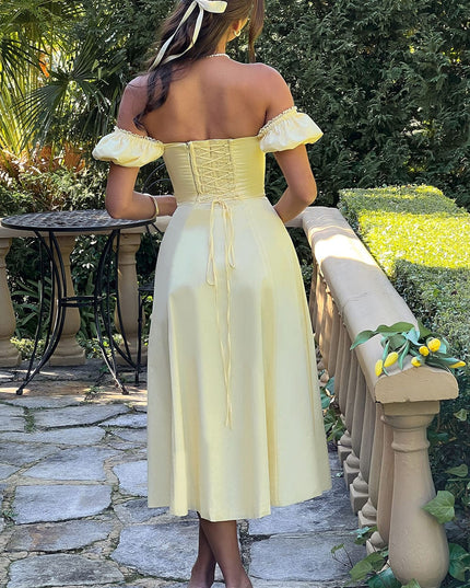 Back view of a light yellow off-shoulder corset midi dress with puff sleeves and lace-up detailing, worn with white heels.