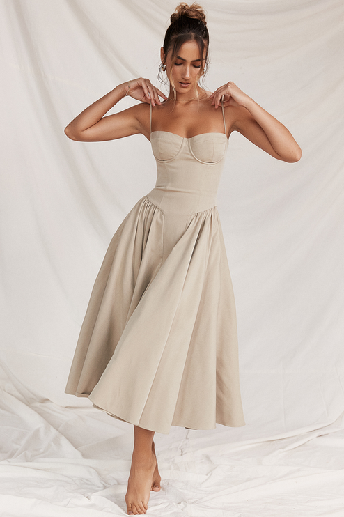 Full-length view of a women's sweetheart neck corset midi dress in light beige, featuring delicate spaghetti straps and a full, flowing skirt.