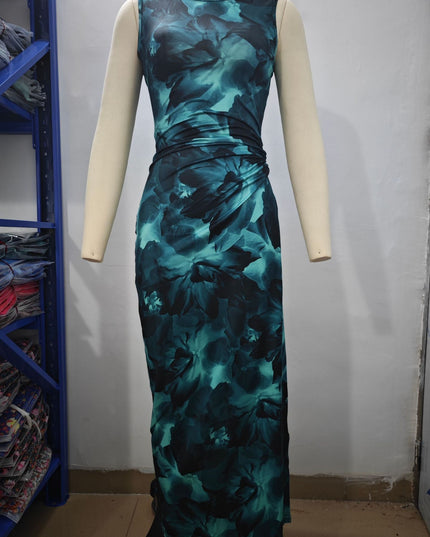 Back view of a women's sleeveless midi dress in a teal and black gradient floral print, with subtle ruching.