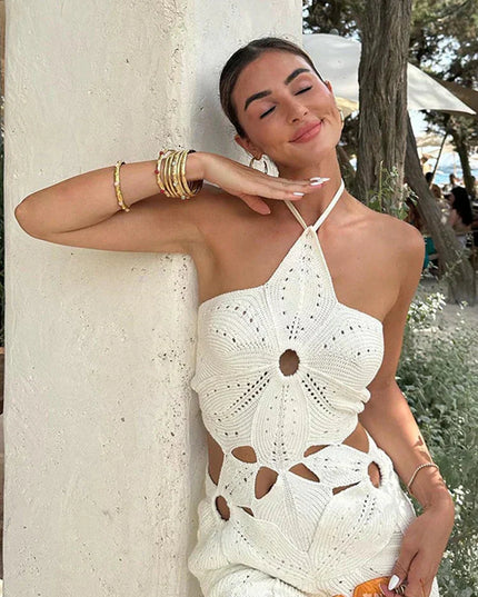 Close-up of a women's white crochet halter neck mini dress, showing the detailed floral pattern and side cut-outs.
