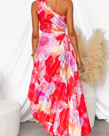 Back view of a vibrant red and pink floral print one-shoulder maxi dress with pleated skirt and cut-out detail at waist.