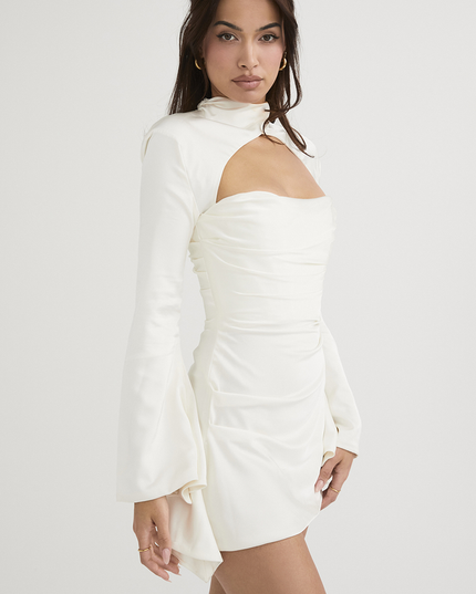 Side profile of the white long sleeve mini dress, showing the elegant cut out and the flow of the satin fabric.
