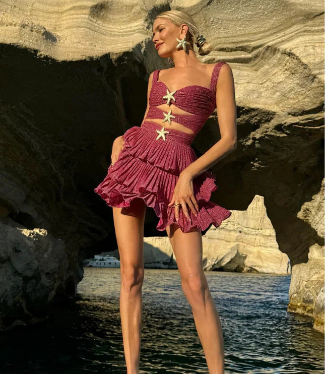 Woman in a shimmery coral summer mini dress with cut-outs and gold starfish details, posing on a boat.