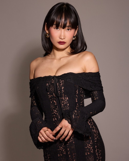 Close-up of a women's black off-shoulder floral lace maxi dress, focusing on the neckline and lace pattern.