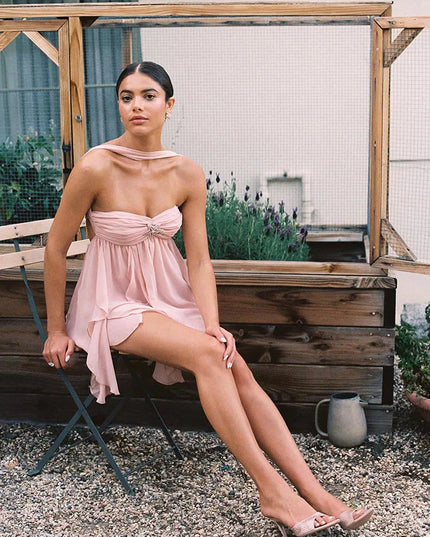Pink ruffle mini dress with a halter neck and strapless bodice, showcasing the layered skirt and designer shoes.