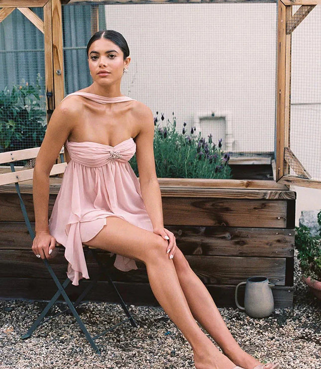 Pink ruffle mini dress with a halter neck and strapless bodice, showcasing the layered skirt and designer shoes.