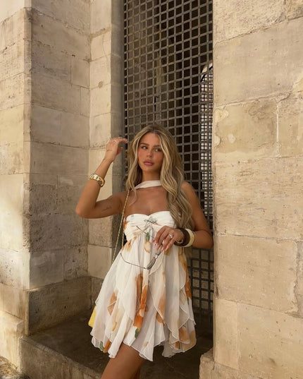 White floral ruffle halter mini dress with subtle orange pattern, featuring a strapless design and front bow detail.