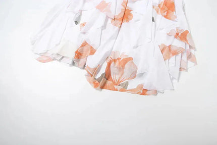 Detail of the white summer floral ruffle mini dress with orange floral print and cascading ruffles on the skirt.