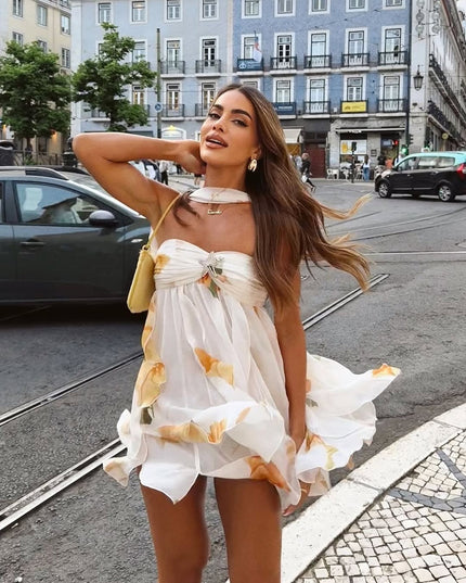 Flowy white summer floral ruffle mini dress with orange details, showcasing the movement of the skirt and halter neck.