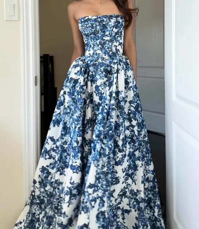 Women's blue floral strapless formal maxi dress with a full skirt, captured in an indoor setting, showcasing its elegant drape.