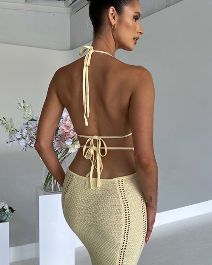 Detailed back view of the light yellow crochet knit maxi dress, highlighting the halter ties and textured skirt.