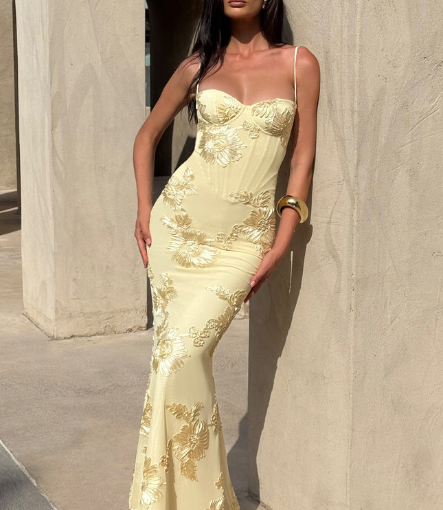 Woman posing in a light yellow floral lace-up maxi dress with gold embroidered flowers, showcasing the elegant fit and flow.