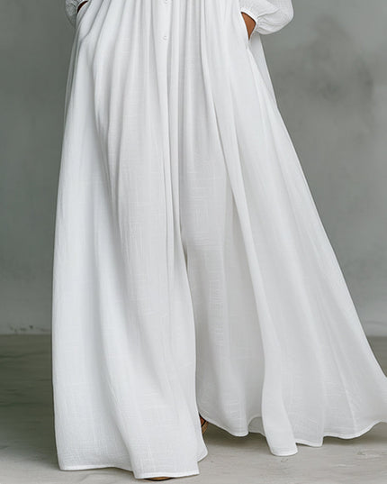 Detail shot of the wide-leg pants on the white button-down jumpsuit, showing flowy fabric and side pockets.