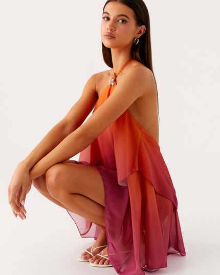 Women's ombre layered chiffon mini dress in orange and pink, posed in a crouching position to show the movement of the fabric.
