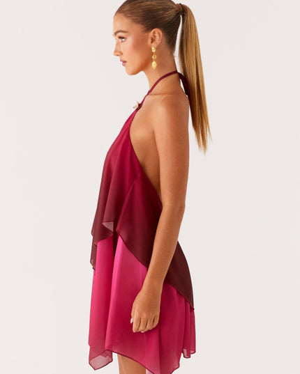 Side profile of a women's halter neck mini dress in burgundy and fuchsia ombre, showcasing the layered chiffon fabric and open back.
