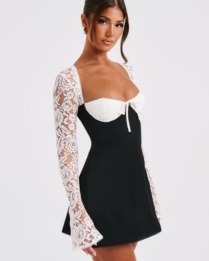 Women's black mini dress with white lace long sleeves and bustier top, featuring a sweetheart neckline and tie detail.