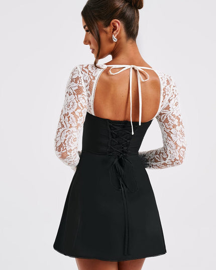 Back view of the black and white lace mini dress, showing a lace-up corset detail and tie closure at the neck.