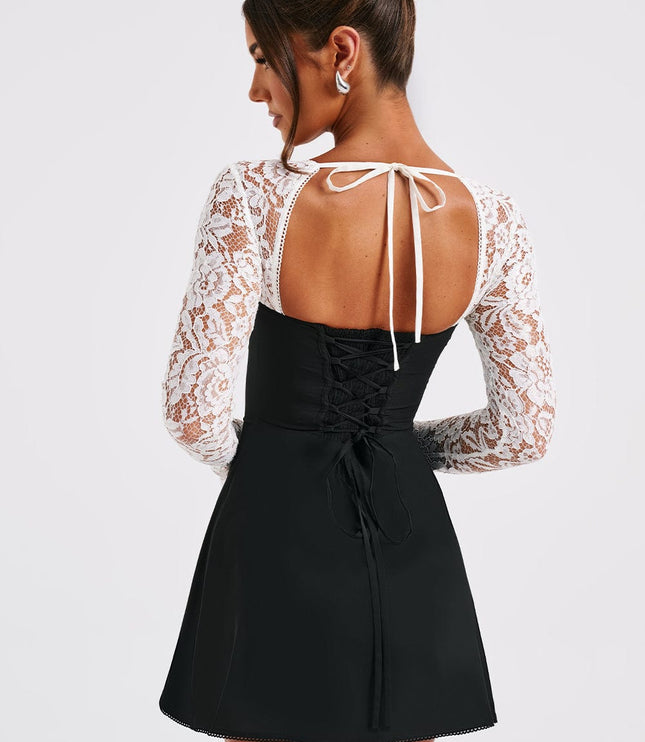 Back view of the black and white lace mini dress, showing a lace-up corset detail and tie closure at the neck.