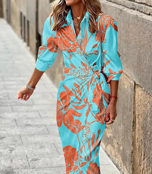 Light blue women's long sleeve V-neck midi dress with an orange tropical leaf print and a knotted detail.