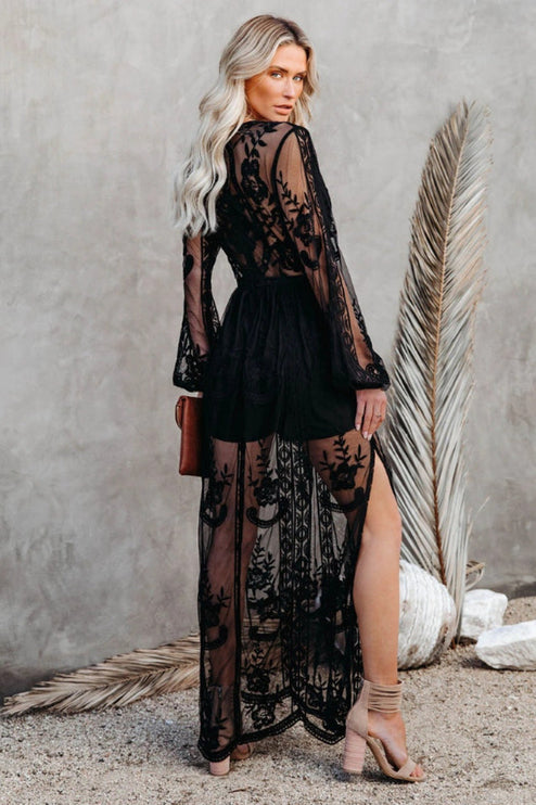 Back view of a women's black lace long sleeve V-neck maxi dress, highlighting the sheer skirt and intricate lace.