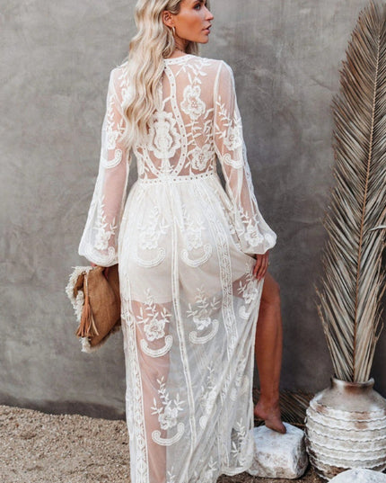 Back view of a white lace maxi dress, showcasing the sheer long sleeves and detailed floral embroidery on the back.