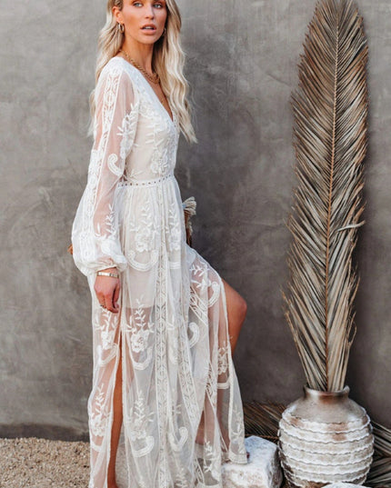 Side profile of a white lace long sleeve maxi dress, showing the flowing skirt, V-neck, and elegant floral design.