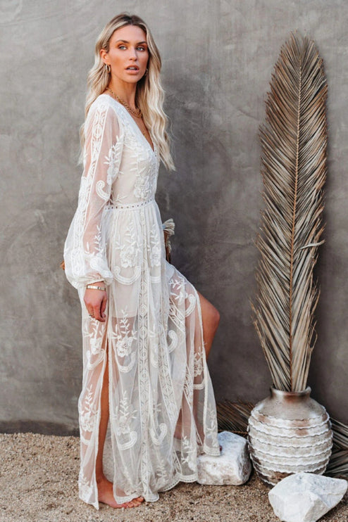 Side profile of a white lace long sleeve maxi dress, showing the flowing skirt, V-neck, and elegant floral design.