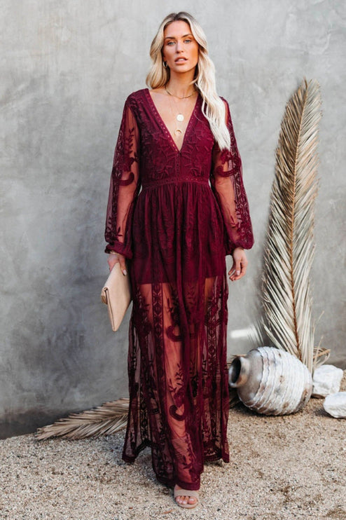 Full-length burgundy lace long sleeve V-neck maxi dress with a sheer overlay and intricate floral embroidery.