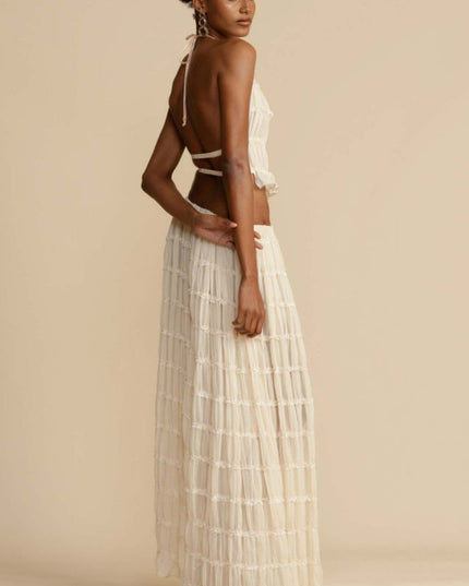 Three-quarter back view of the women's ivory halter ruffle trim crop top and maxi skirt set, showcasing the garment's silhouette.